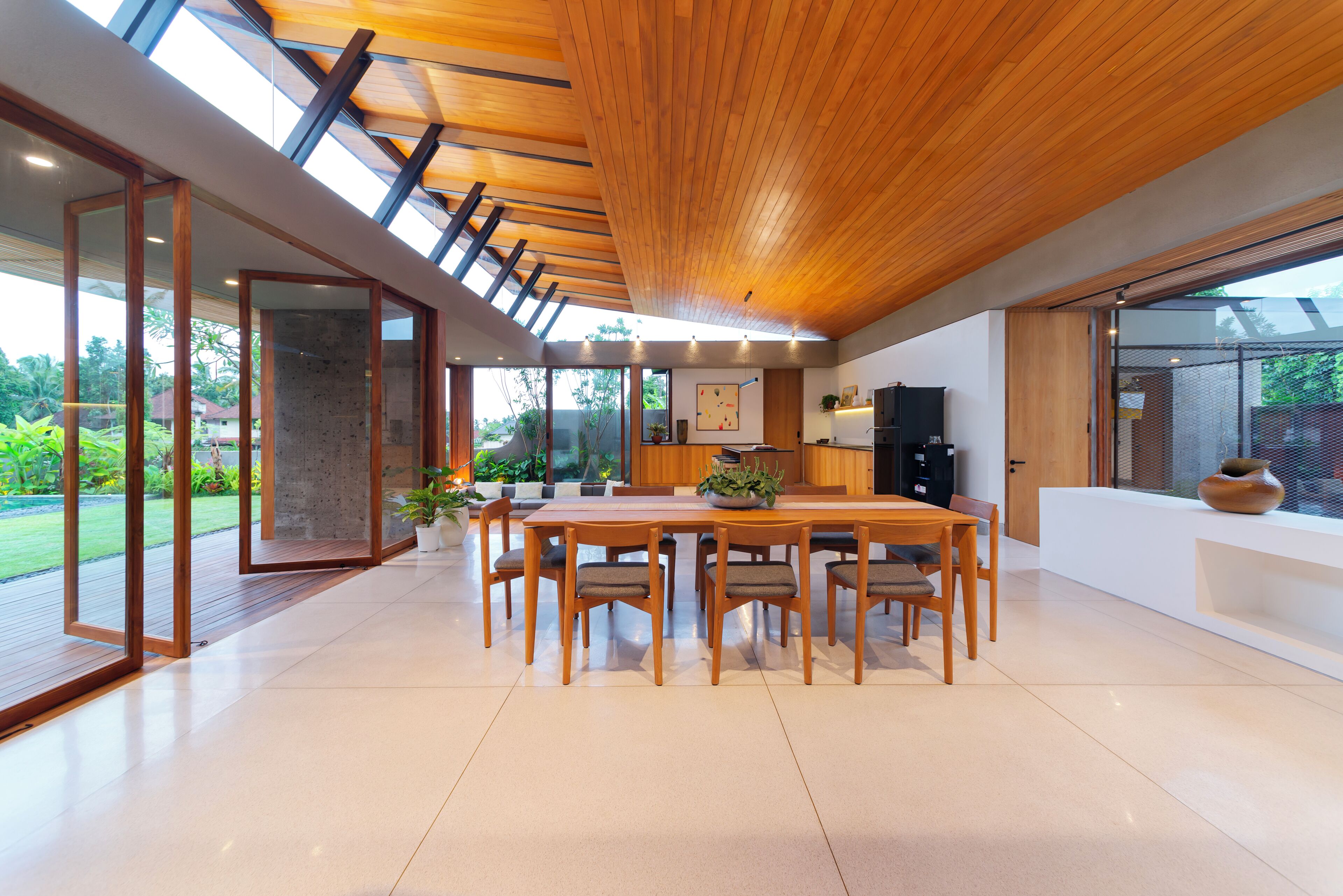 A modern kitchen with a large island, wooden ceiling, and large windows.