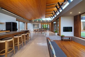 Eine moderne Küche mit Holzbarhocker, einem Essbereich und einem großen Fenster mit Tageslicht.