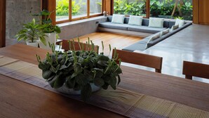 A modern interior with a dining area, large windows, and a view of greenery outside. - Indica Luxury Villa Ubud (Ubud)