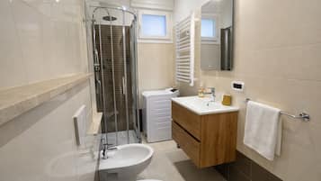 A modern bathroom with a shower, bidet, sink, and toilet.