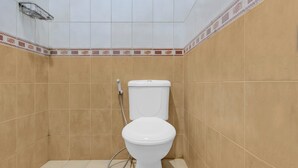 A bathroom with a toilet, tiled walls, and a shower area.