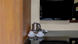 A kitchen area with a coffee maker, a kettle, and a remote control on the counter.