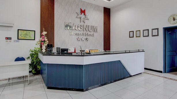 A reception desk with a sign reading 'MAGNUM Resort & Hotel,' a clock, framed certificates, and a blue door.
