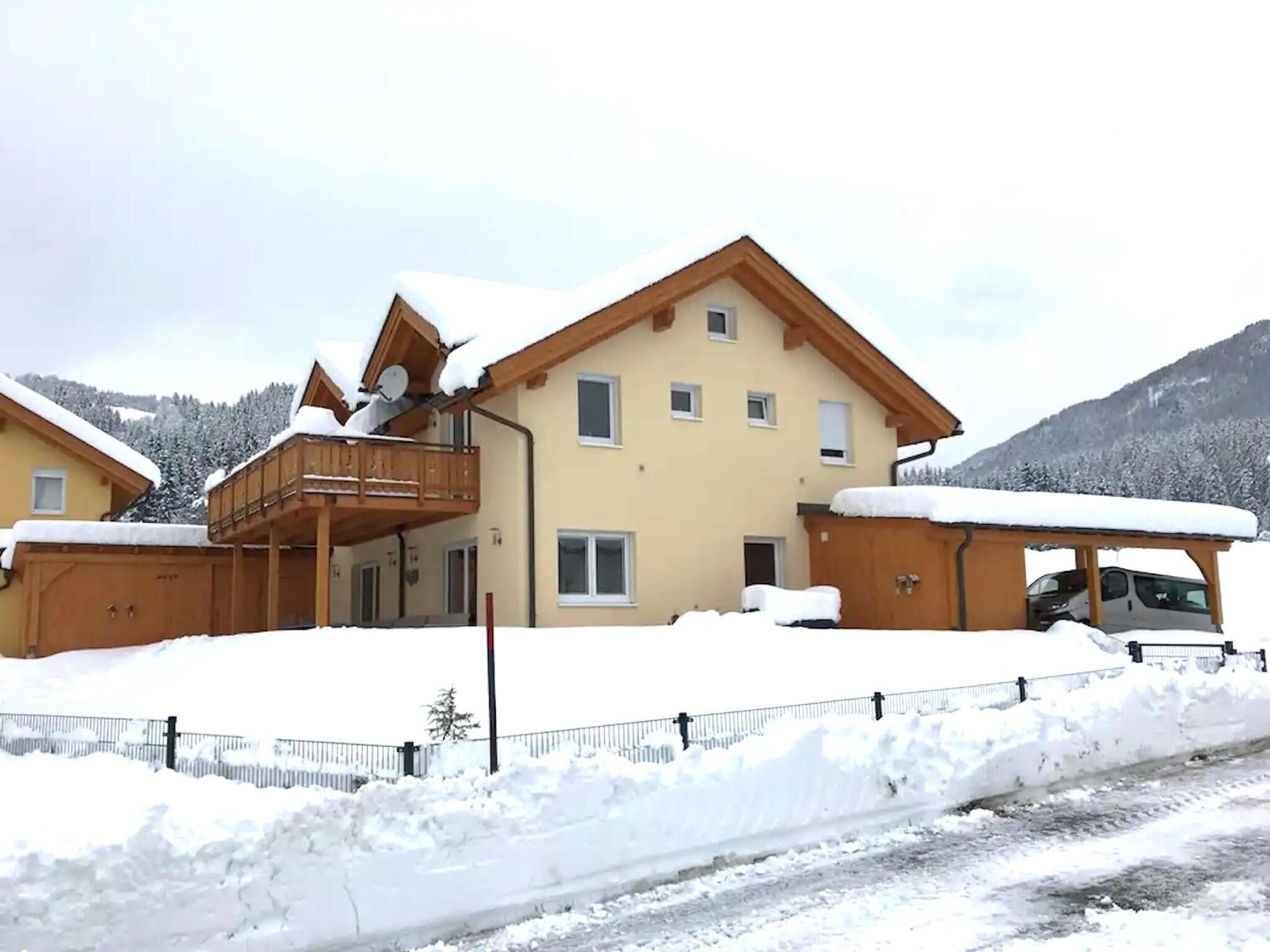 A two-story building with a balcony, a garage, and a snow-covered landscape.