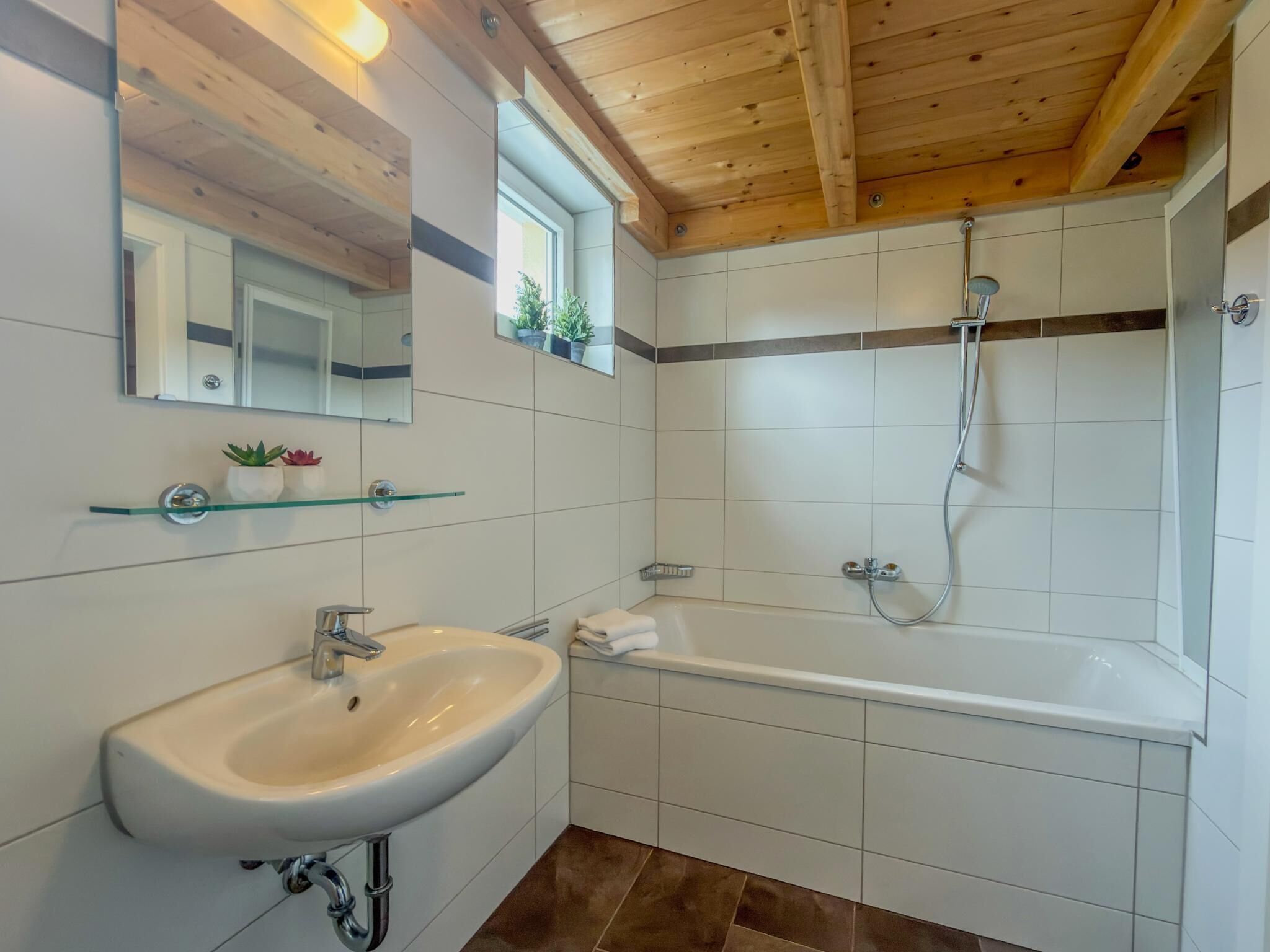 Une salle de bain avec un lavabo, un miroir, une douche et des murs carrelés.