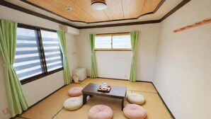 A tatami mat room with a low table, cushions, and a window with curtains. - START HOUSE PIAA-Ski IN Ski OUT (Minamiuonuma)