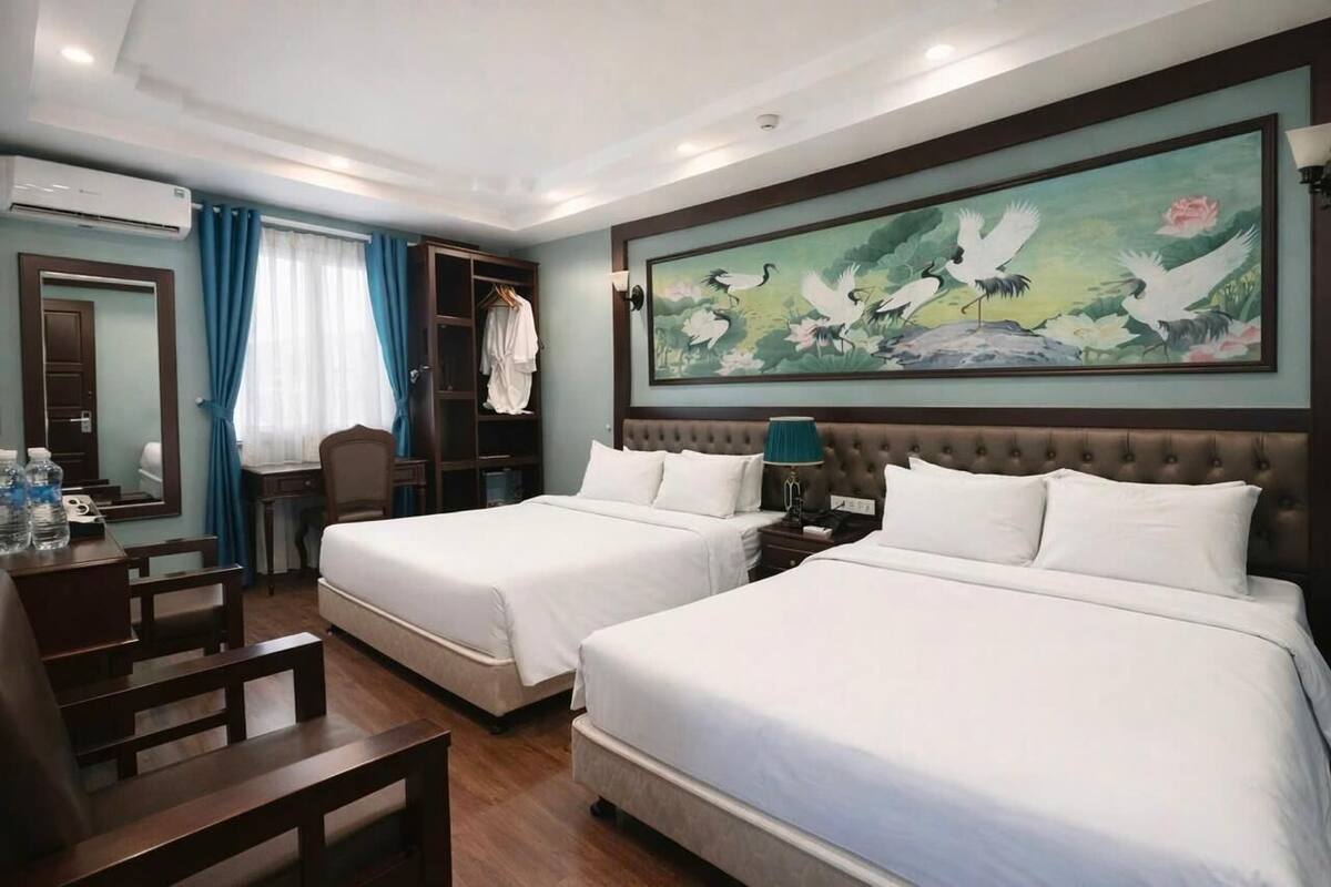 Habitación de hotel con dos camas, un escritorio, una silla, un armario y un cuadro en la pared.