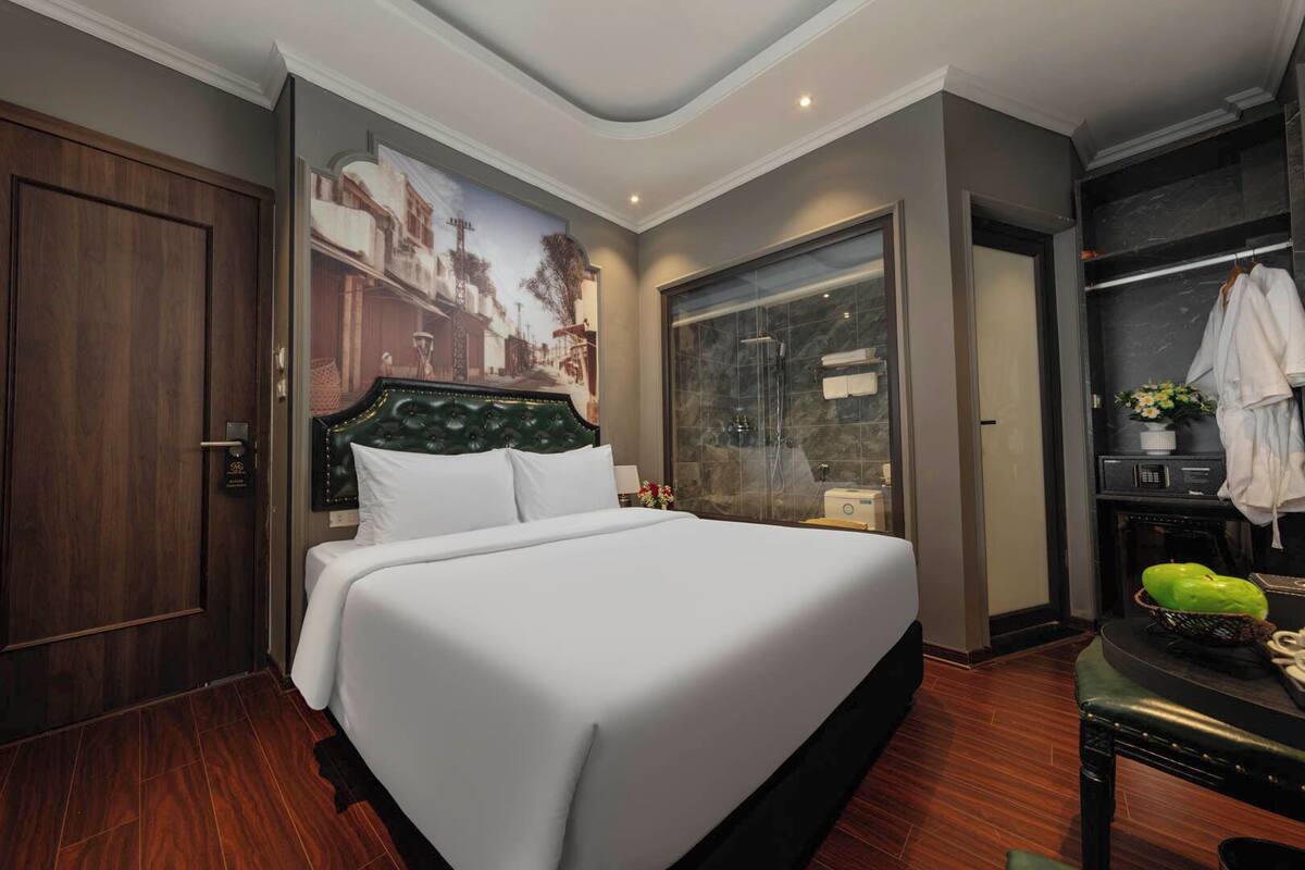 Habitación de hotel con una cama grande, zona de ducha, escritorio con silla y armario.