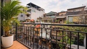 A balcony with a potted plant, overlooking a street with buildings and a clear sky. - Hanoi Sense Legend Hotel & Travel (Hanoi)