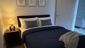 A bedroom with a bed, bedside table, lamp, and wall art. - Apartment 65m2 - comfortable, stylish, pet friendly, easy access to shops. (São Paulo)