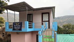 Un bâtiment aux couleurs rose et bleu, sur lequel on peut lire une enseigne indiquant qu’il s’agit d’un hébergement situé dans un cadre naturel préservé.