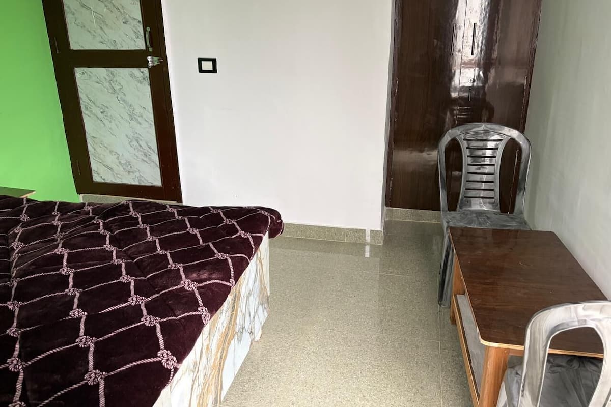 A room with a bed, a wooden table, and a chair.