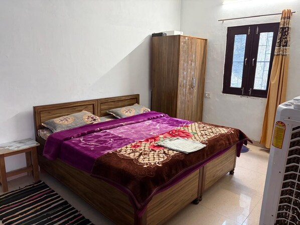 A bedroom with a bed, wooden wardrobe, and a window with curtains. - Nature Valley (Marchula)