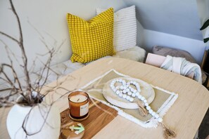 Ein Zimmer mit einem Holztisch, einer Kerze, einem dekorativen Teller und einer Vase mit Zweigen.