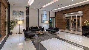 Een moderne lobby met een zithoek, een receptiebalie en een trap naar een verdieping boven.