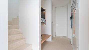 Un escalier menant à un palier où se trouvent une étagère et une porte.