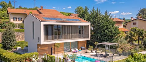 A modern two-story house with a swimming pool, solar panels, and a well-maintained garden.