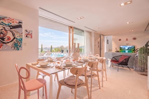 Un comedor moderno con vistas a la piscina, muebles contemporáneos y un televisor de pantalla plana.