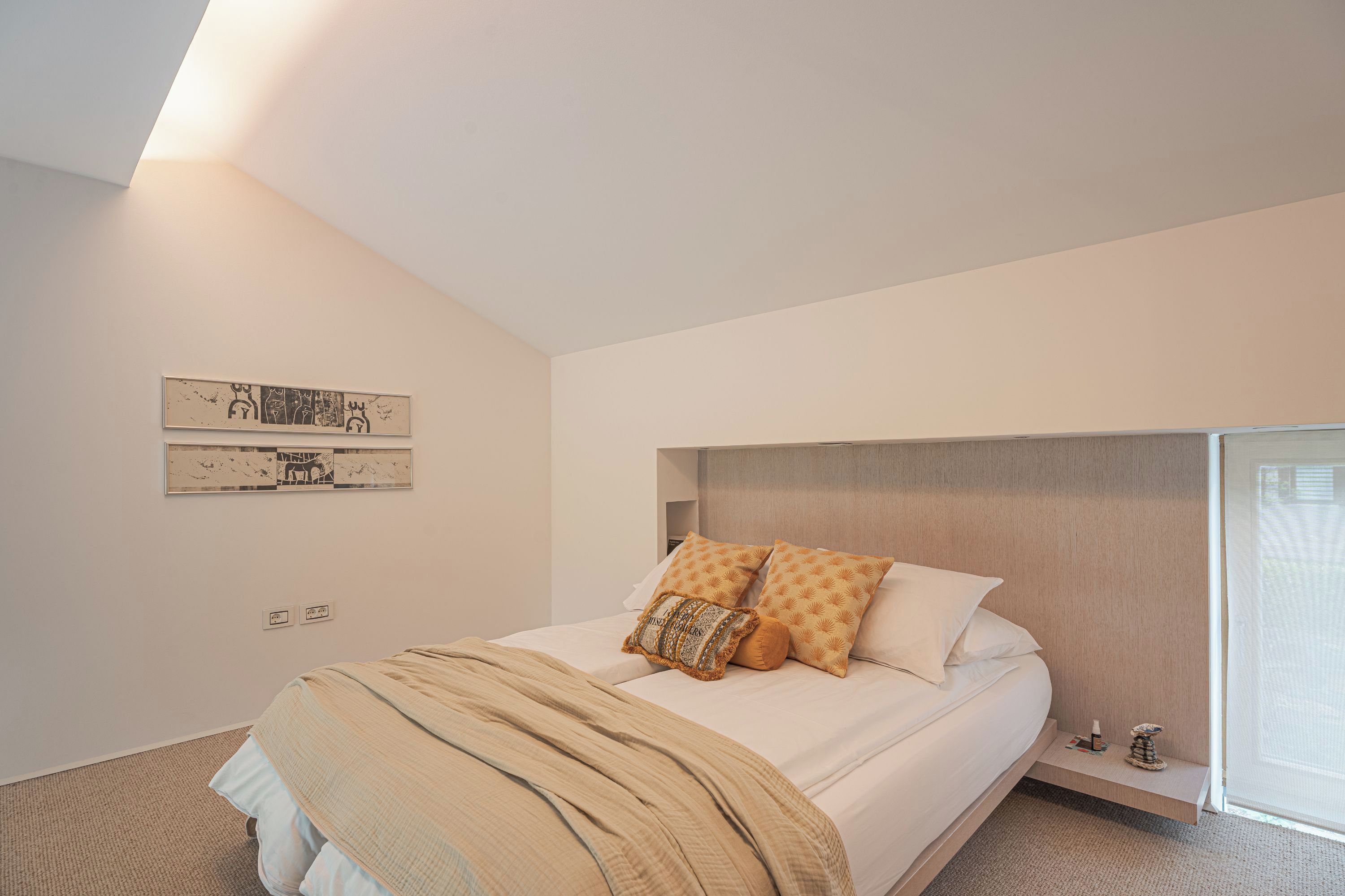 Ein modernes Schlafzimmer mit einem großen Bett, einem Kopfteil, einem kleinen Nachttisch und einem an der Wand befestigten Kunstwerk.