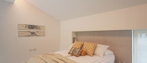 Un dormitorio moderno con una cama grande, cabecera, mesita de noche pequeña y una obra de arte colgada en la pared.
