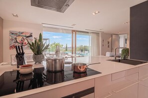 Una cocina moderna con una isla central, electrodomésticos de acero inoxidable y vistas a una piscina.