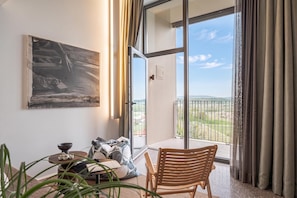 A room with a large window, a painting on the wall, a table with a bowl and a plant, and a chair. - Alma Vista Villa in Goriska Brda Pool & Spa (Brda)