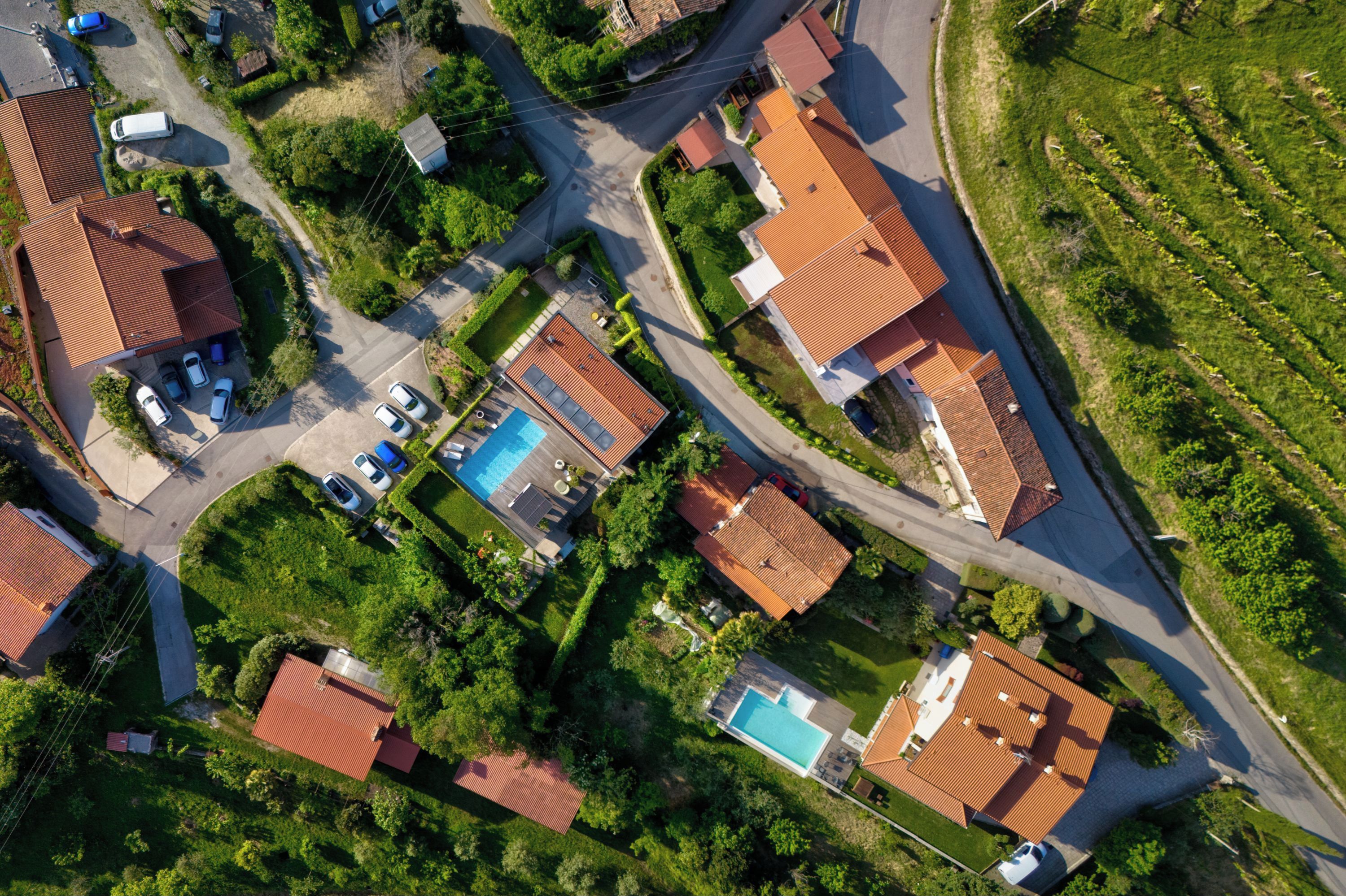 An aerial view of a residential area with multiple houses, roads, and a swimming pool.