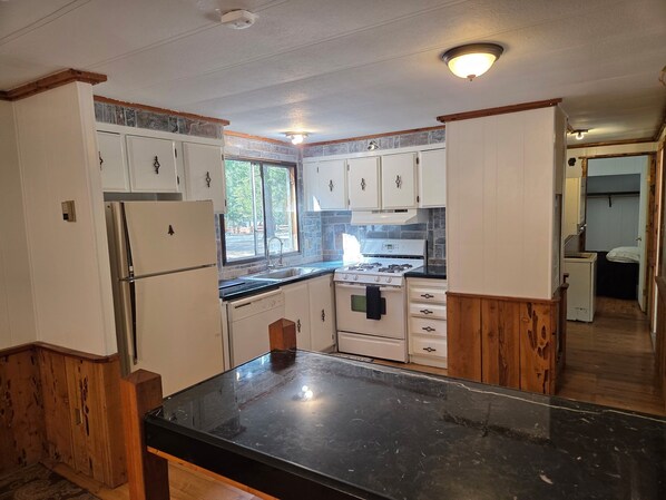 A kitchen with white cabinets, a black countertop, a stove, and a refrigerator.