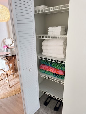 A white closet with shelves holding folded towels and a pair of black slippers. - Spacious 4-bedroom house in lovely Sarasota with Private Pool (Sarasota)