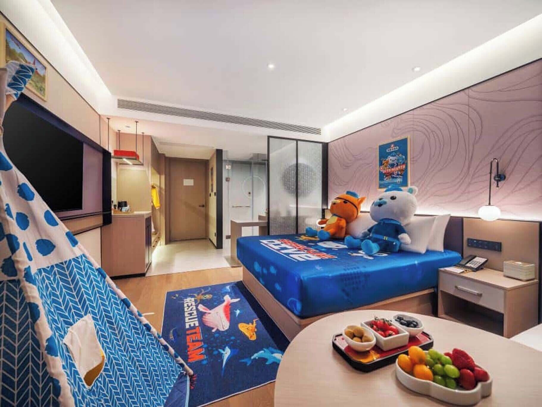 Une chambre d’hôtel équipée d’un lit, d’un bureau, d’une chaise, d’une télévision, d’une armoire et d’une porte.