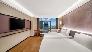A modern hotel room with a large TV, a sofa, a small table, and a view of the cityscape. - MAISON NEW CENTURY (Ningbo)