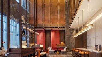 Un interior moderno con una zona de bar, asientos y vistas a través de un muro de cristal.