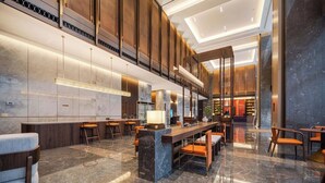 A spacious lobby with a long reception desk, multiple seating areas, and a modern interior design. - MAISON NEW CENTURY (Ningbo)