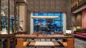 A spacious lobby with a long wooden reception desk, seating area, and large windows offering views of the cityscape. - MAISON NEW CENTURY (Ningbo)