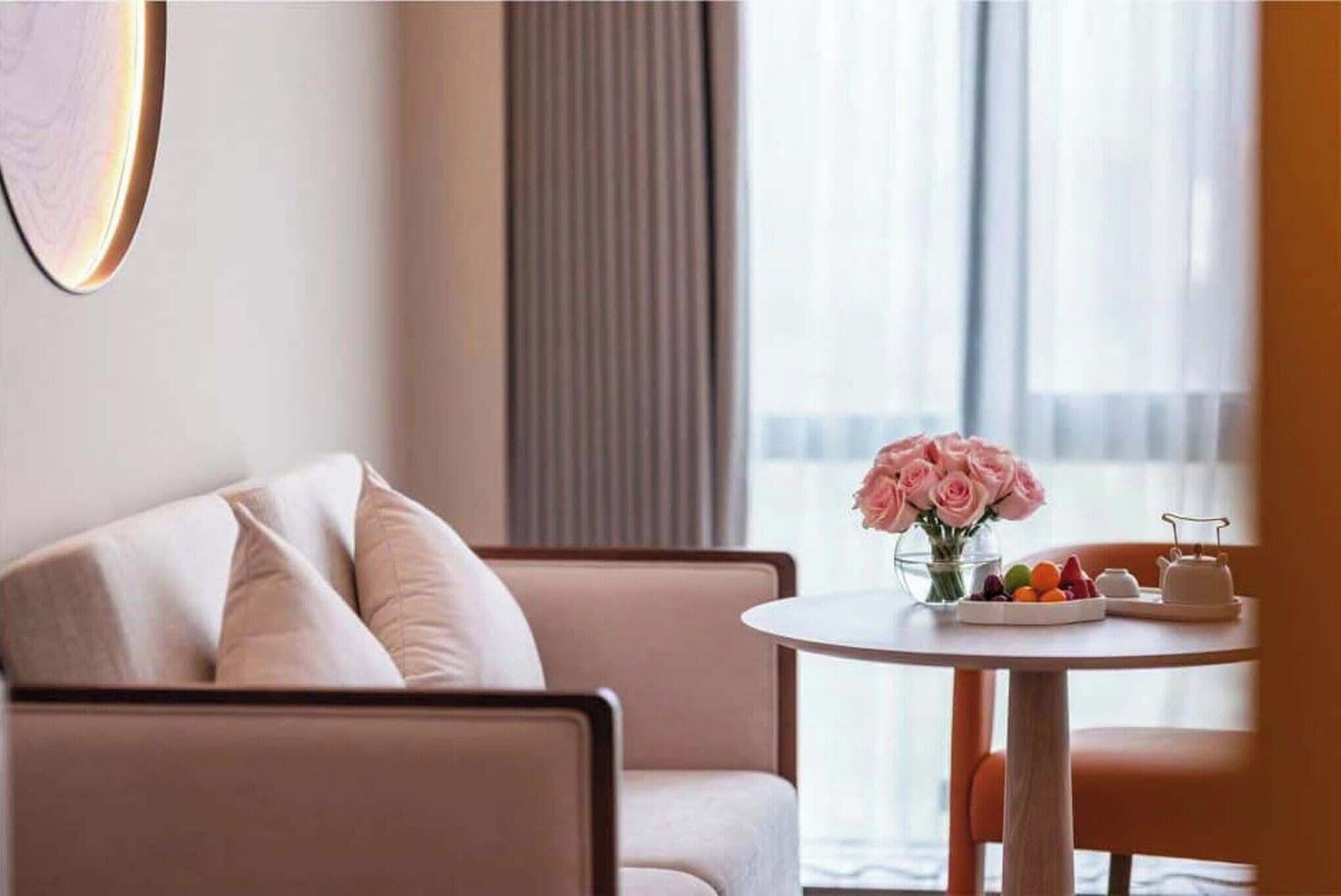 Habitación de hotel moderna con sofá, una mesa redonda con un florero y vistas por la ventana.