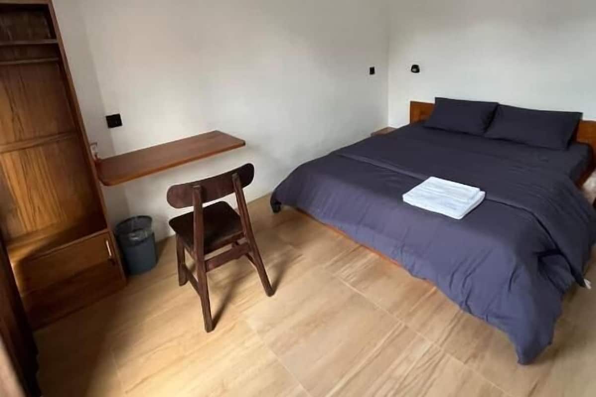 Un dormitorio con una cama, un escritorio de madera y una silla.