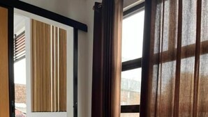A room with a wooden table, a sliding door, and a view of the outside. - Kali Code Home (Yogyakarta)