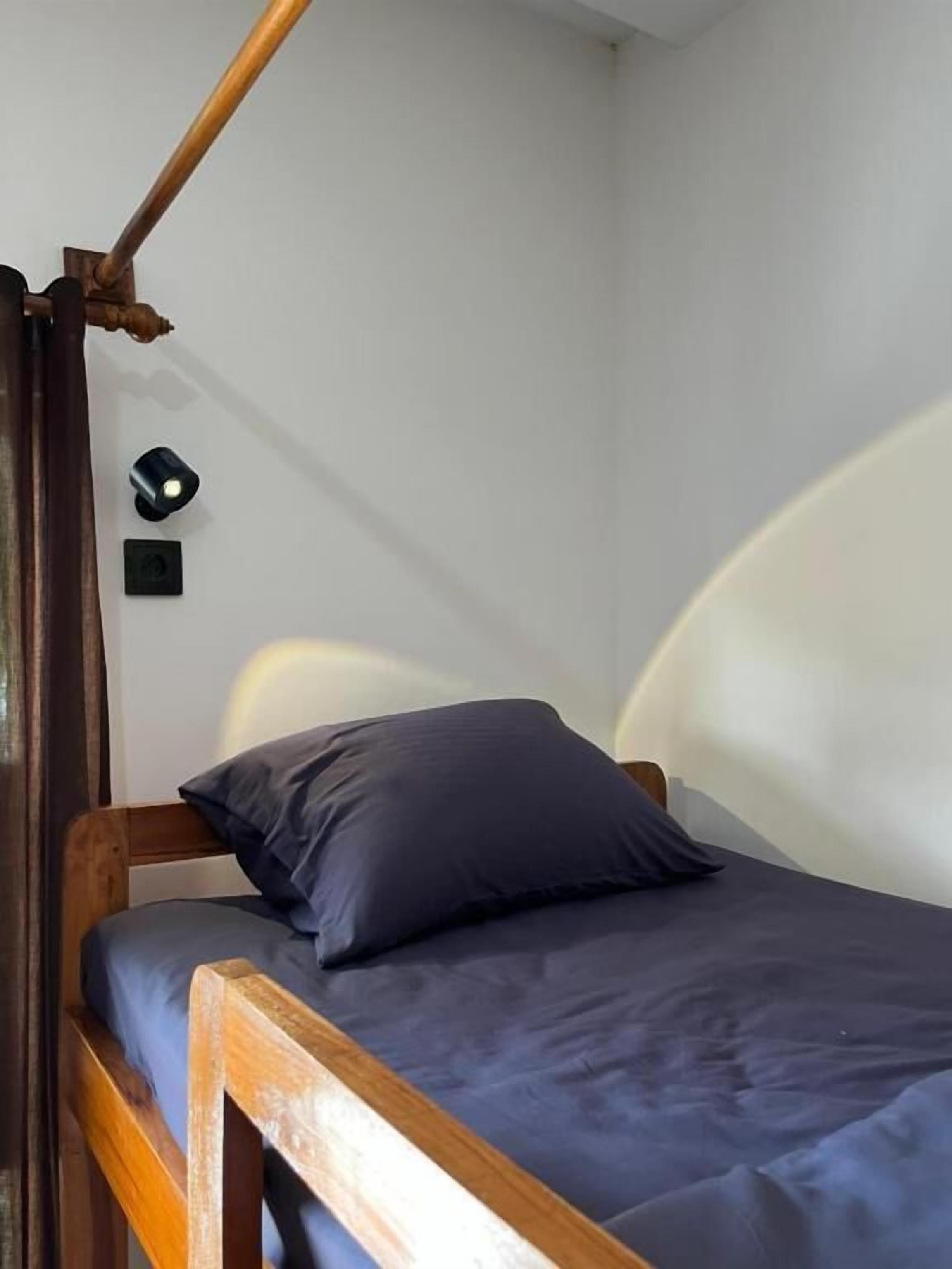 Un lit simple avec un cadre en bois, un matelas bleu foncé et un oreiller assorti.