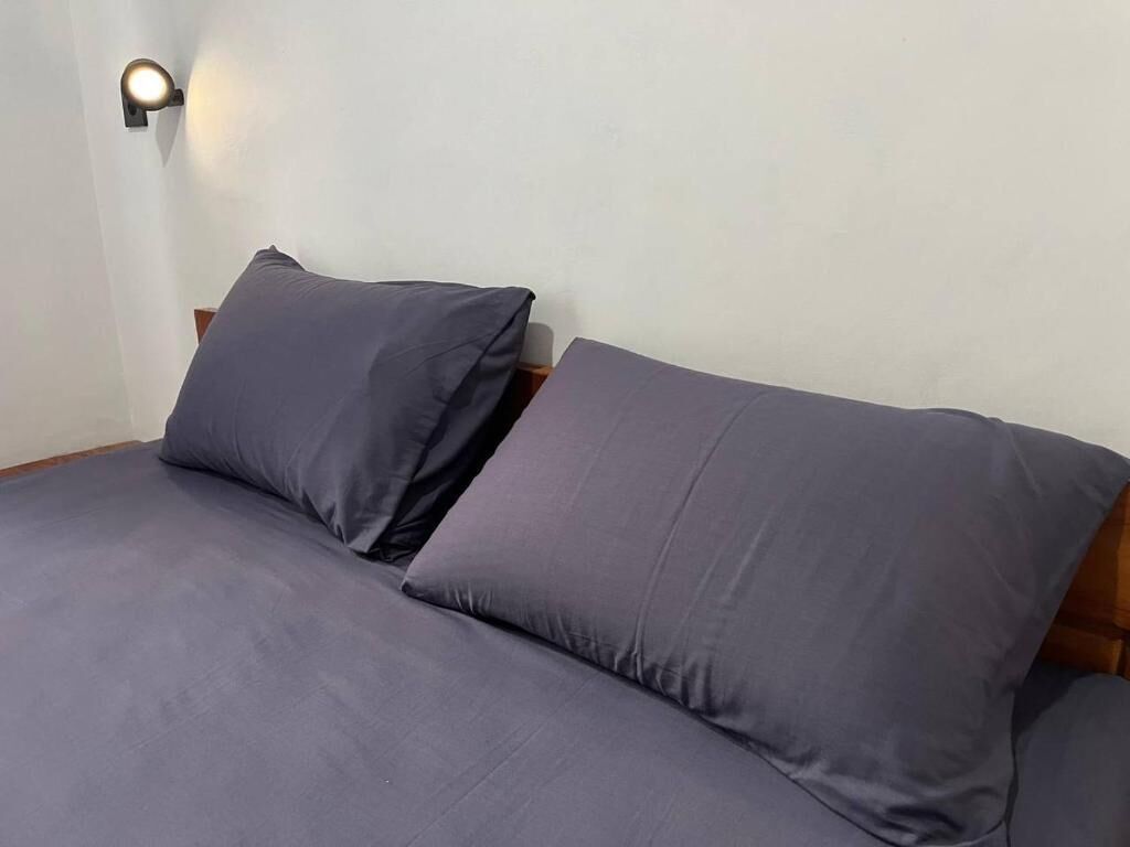 A bed with two pillows and a wall-mounted light fixture.