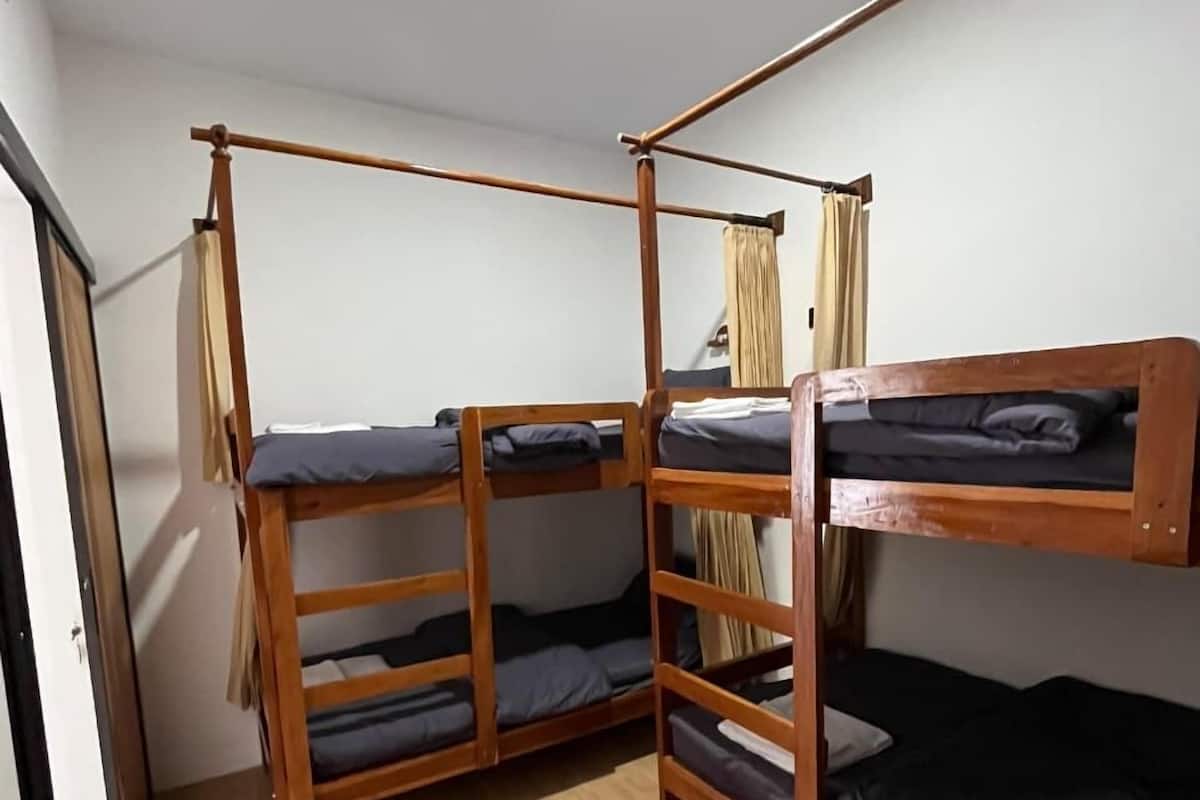 Un dormitorio con literas, suelo de madera y ventana con cortinas.