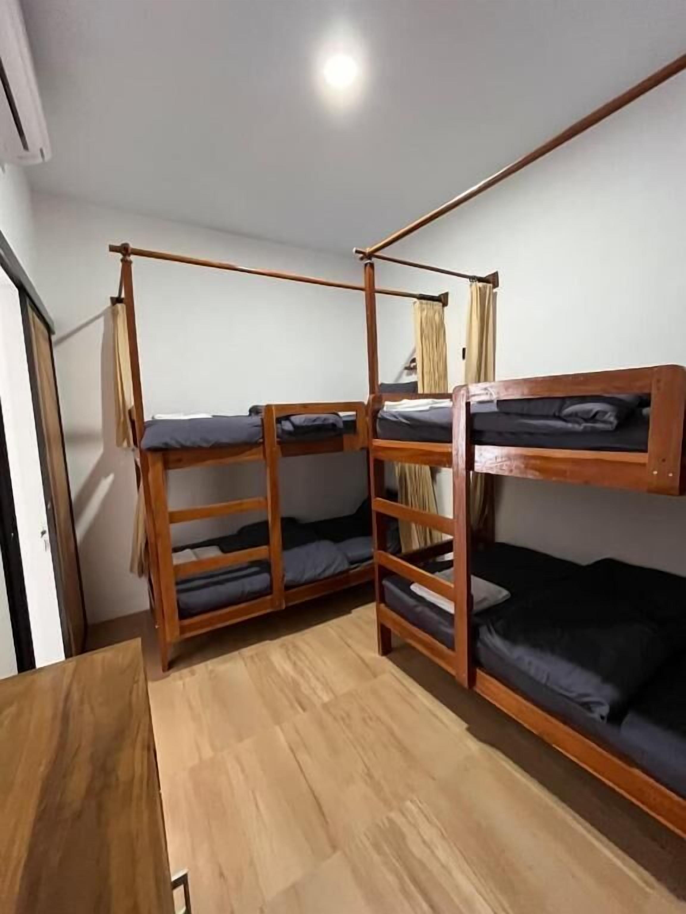 A room with bunk beds, wooden flooring, and a door.