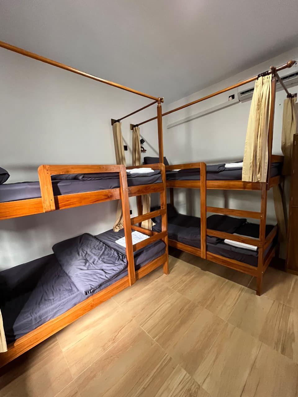 A bunk bed room with wooden frames and grey bedding.