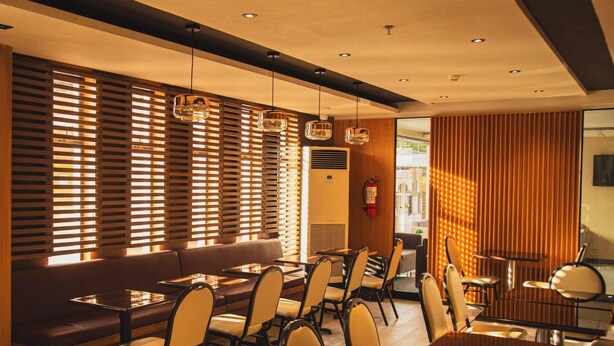 A modern dining area with wooden slats, pendant lights, and a fire extinguisher. - Hotel 801 Inc. (Cagayan de Oro)