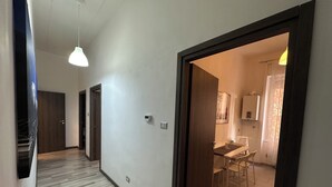 A hallway with wooden flooring, a dining area with a table and chairs, and a kitchen visible through an open door. - Bright central apartment (foggia)