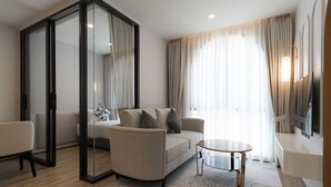 Una sala de estar moderna con un sofá, una mesa de centro, un televisor y un separador de vidrio.