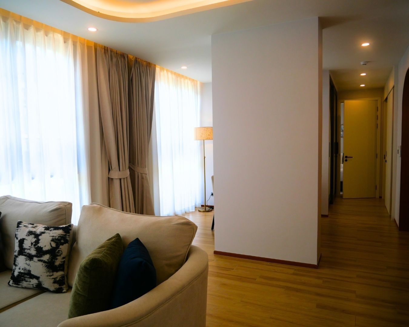 Un salon avec un canapé, une lampe et un couloir menant à une porte.