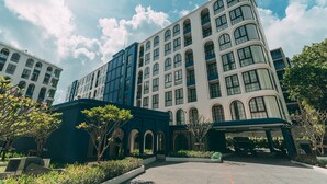 Un hotel de varios pisos con fachada curva, ventanas amplias y un área de entrada techada.