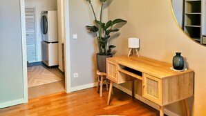 Una habitación con un escritorio de madera, una planta en maceta, un espejo y luces colgantes.