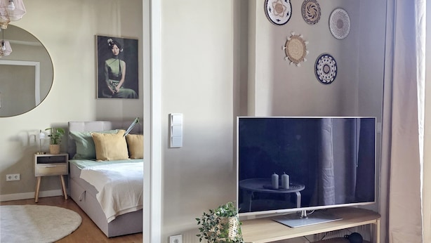Una sala de estar moderna con una cama, televisor y decoración en la pared.