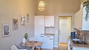 Una cocina moderna con armarios blancos, un comedor con mesa redonda y una lámpara colgante.